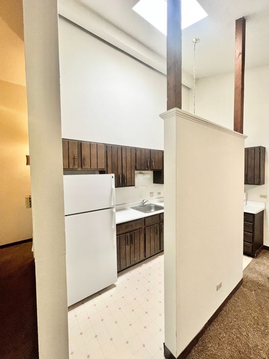 Charming kitchen with rustic wood cabinetry, high ceilings, and modern lighting in an inviting apartment space.