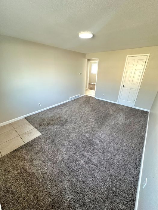 Bright and inviting room with fresh carpet, neutral toned walls, and a modern light fixture, perfect for a cozy living space.
