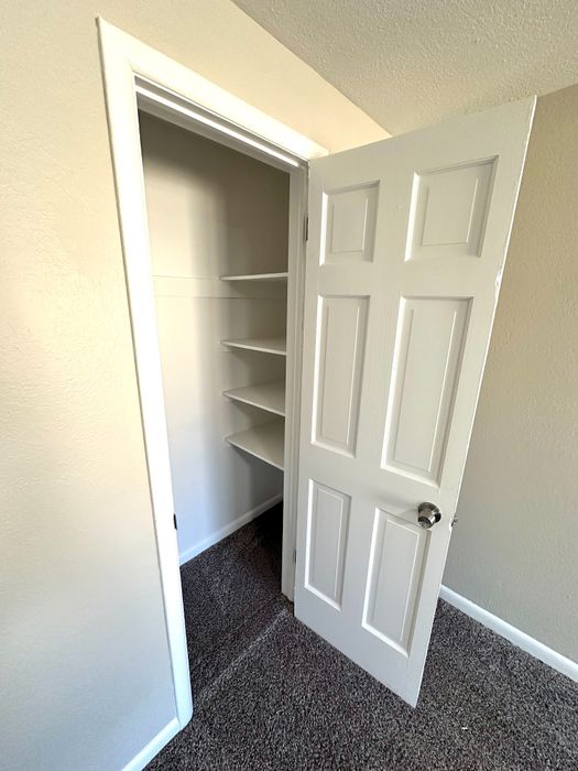 Cozy walk-in closet with built-in shelving and elegant white door, perfect for organized living.