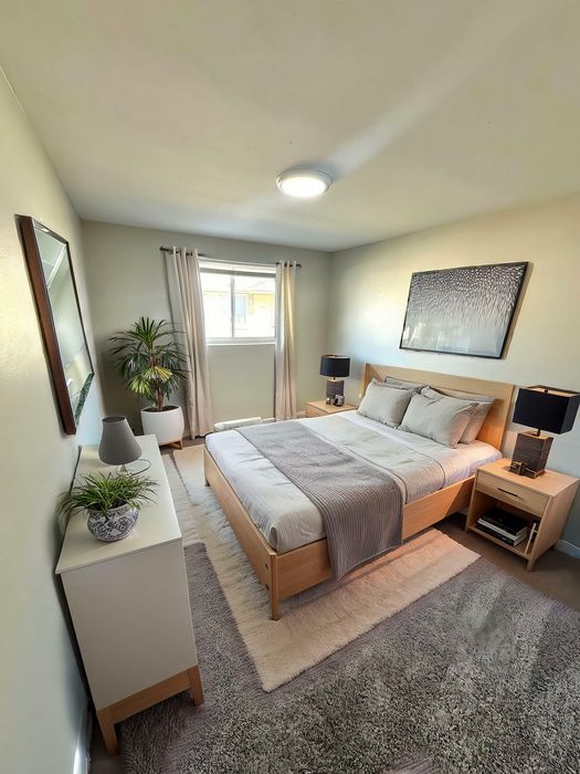 Inviting bedroom with modern decor, featuring a cozy bed, stylish side tables, and a serene ambiance enhanced by natural light and greenery.