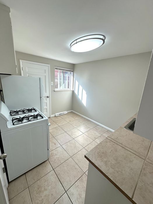 Bright, modern kitchen with sleek tile flooring, large windows for abundant natural light, and stylish overhead lighting.