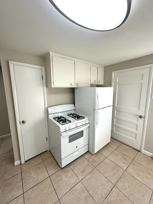 Charming kitchen with classic white appliances, ample cabinet storage, and modern tiled flooring.