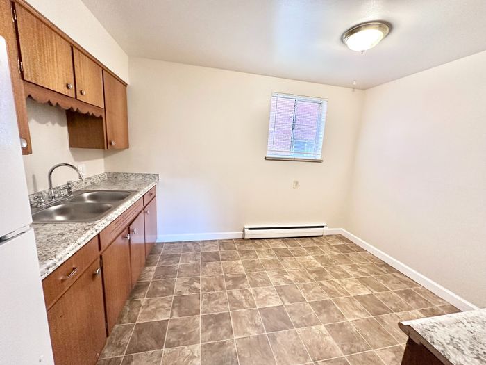 Bright, modern kitchen with sleek countertops, dual sink, and elegant wood cabinets; perfect for culinary creativity.