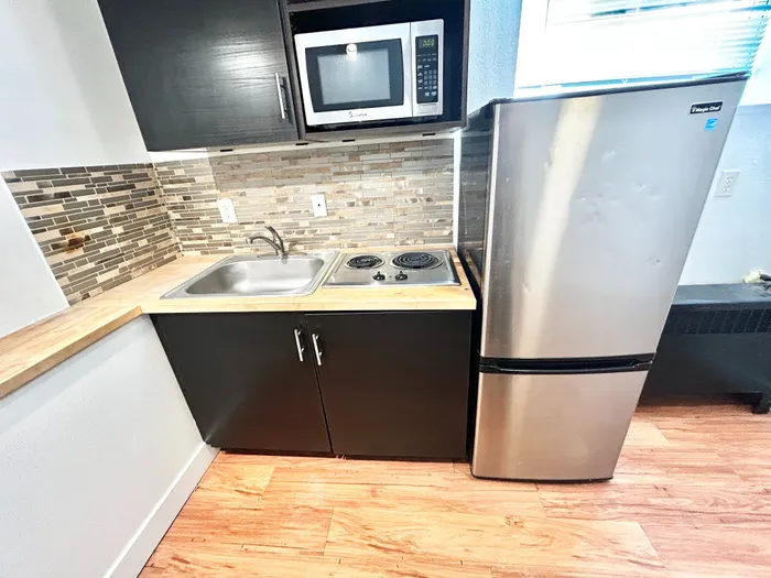 Modern kitchen nook with sleek stainless steel appliances, stylish tile backsplash, and compact cooking area.