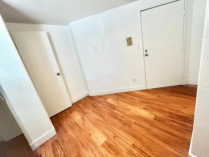 Elegant entryway with polished hardwood floors and modern white doors, offering a warm and inviting atmosphere.