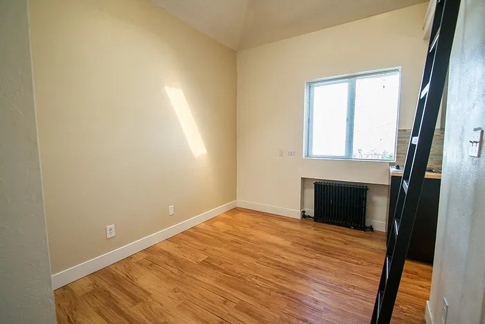 Bright and cozy room with stylish wooden flooring and a large window inviting natural light.