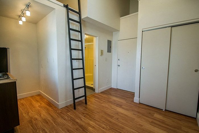Chic studio apartment with modern loft ladder, stylish wooden flooring, and bright lighting.