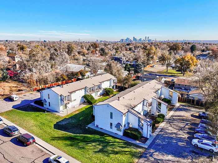 Charming apartment complex surrounded by lush greenery, offering picturesque views of city skyline and vibrant neighborhood.