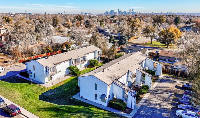 Charming apartment complex with lush greenery, situated in a peaceful neighborhood, offering stunning city skyline views.