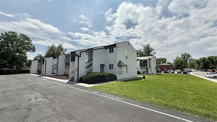 Charming apartment complex with modern architecture, lush green lawn, and ample parking in a serene neighborhood setting.