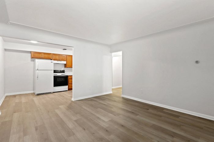 Bright and inviting kitchen area with wooden cabinetry, white appliances, and elegant flooring, perfect for a modern lifestyle.
