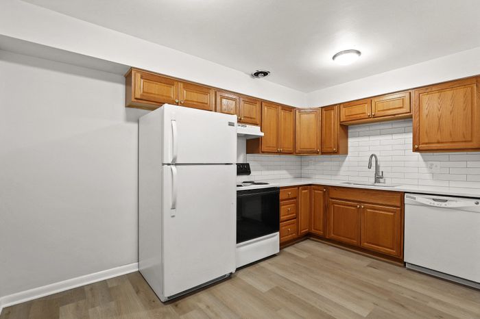 Bright and inviting kitchen with modern white appliances, elegant wooden cabinets, and sleek countertops. Ideal for culinary creativity.