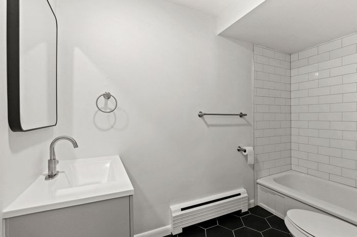 Modern bathroom featuring a sleek white vanity, chrome fixtures, and a stylish tiled bathtub.