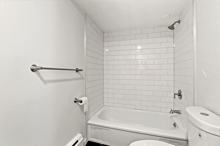 Bright and modern bathroom featuring sleek white subway tiles and a spacious bathtub, offering a clean and refreshing ambiance.