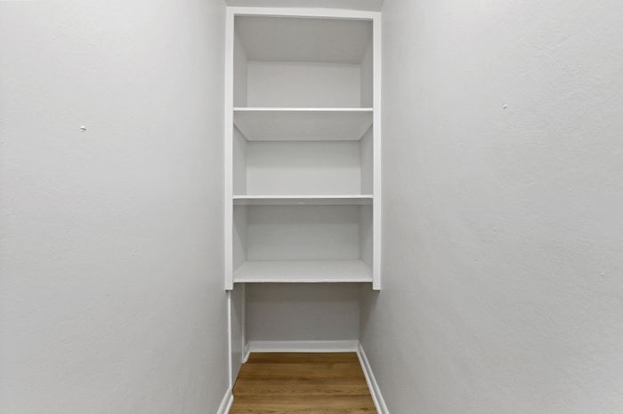 Bright, spacious walk-in closet with minimalist shelving, perfect for organizing your wardrobe and accessories.