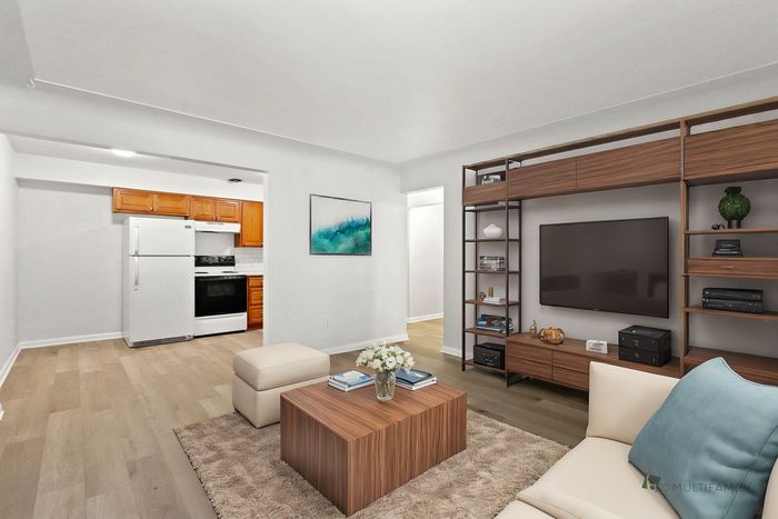 Modern open-concept living room with stylish shelving, comfy seating, and a spacious adjacent kitchen.
