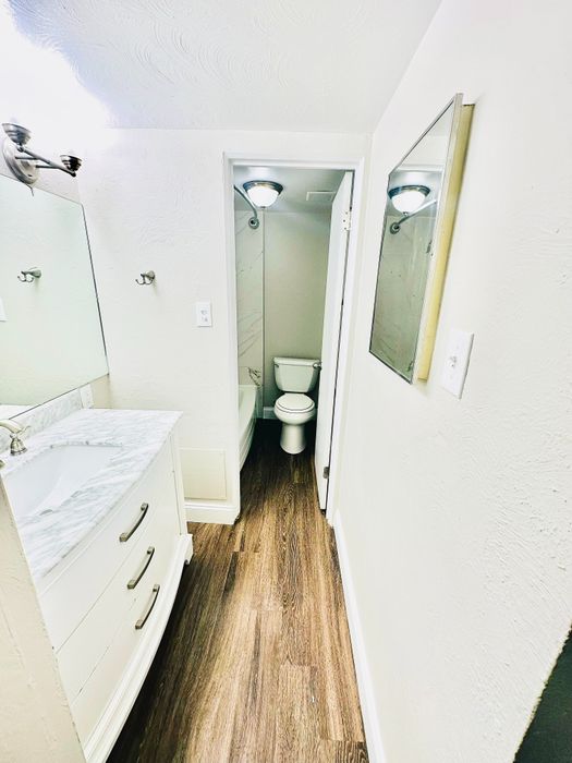 Elegant bathroom featuring sleek marble vanity, stylish light fixtures, and warm wood flooring.