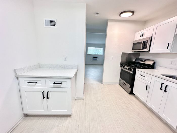 Bright, modern kitchen with sleek white cabinets, stainless steel appliances, and elegant countertops flowing into a spacious open living area.