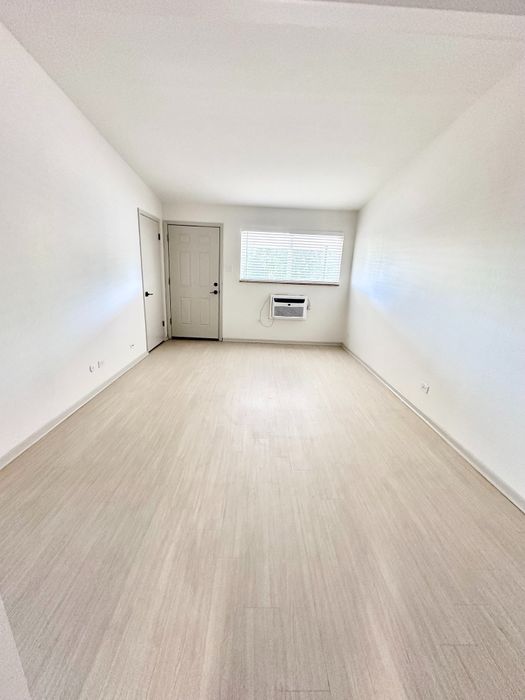 Bright and inviting room with sleek flooring, large window, and modern air conditioning unit.