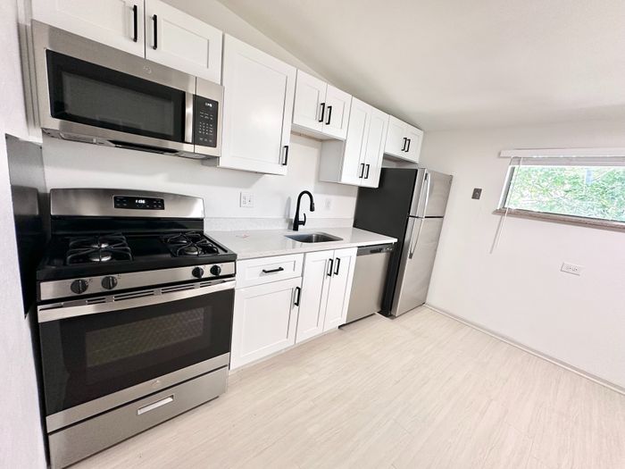 Modern kitchen with sleek stainless steel appliances, elegant white cabinetry, and ample natural light.