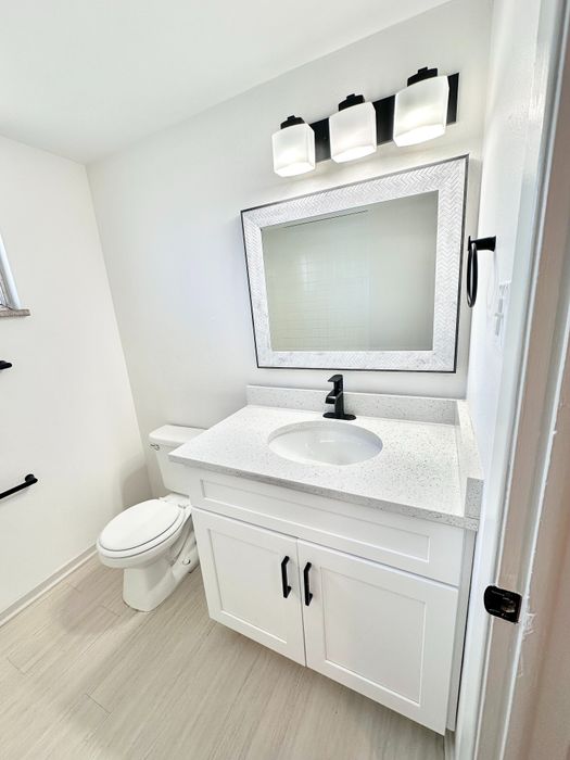 Modern bathroom with sleek white vanity, elegant mirror, and stylish lighting fixtures.