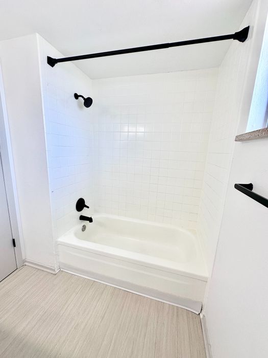 Elegant bathroom featuring a pristine white bathtub with modern black fixtures and sleek tile work.