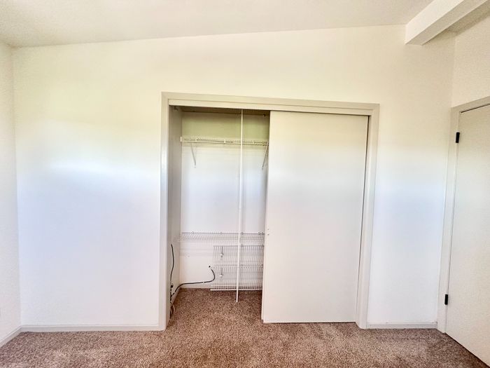 Bright and spacious closet with sliding doors, showcasing ample storage space and modern design.