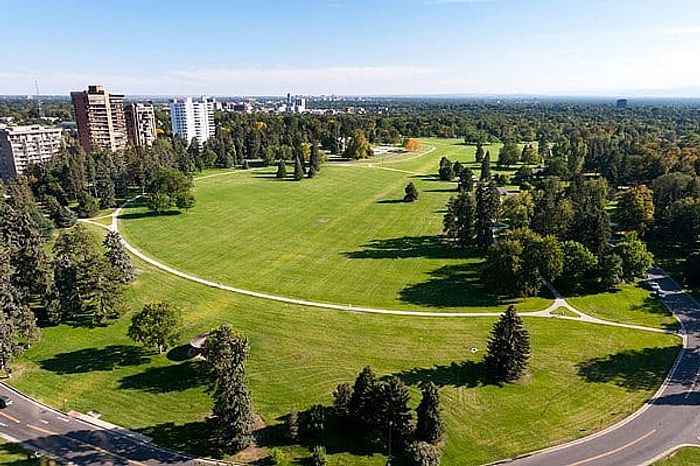 Scenic aerial view of a lush green park surrounded by towering buildings and extensive greenery, ideal for rejuvenating urban living.