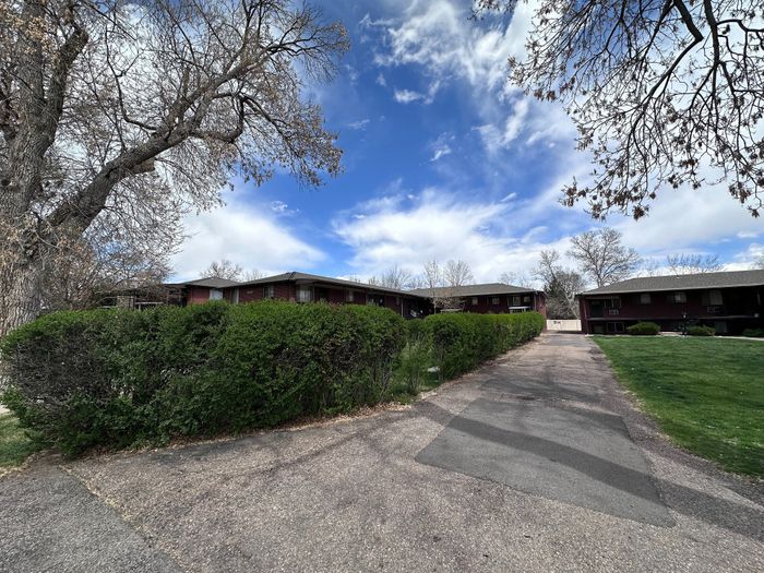 Charming apartment complex surrounded by lush greenery and expansive blue skies, perfect for tranquil living.