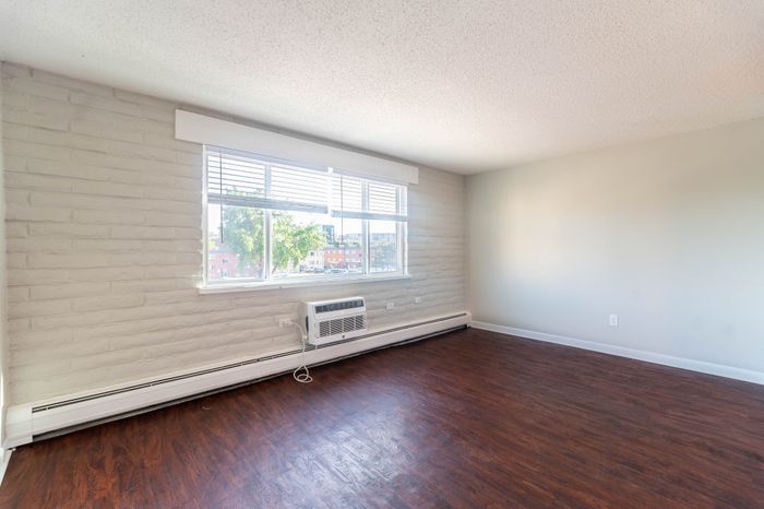 Bright living area with large window and elegant hardwood floors, offering a welcoming and spacious environment.