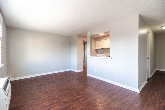 Bright and airy living space with modern hardwood floors leading to a cozy kitchen area.