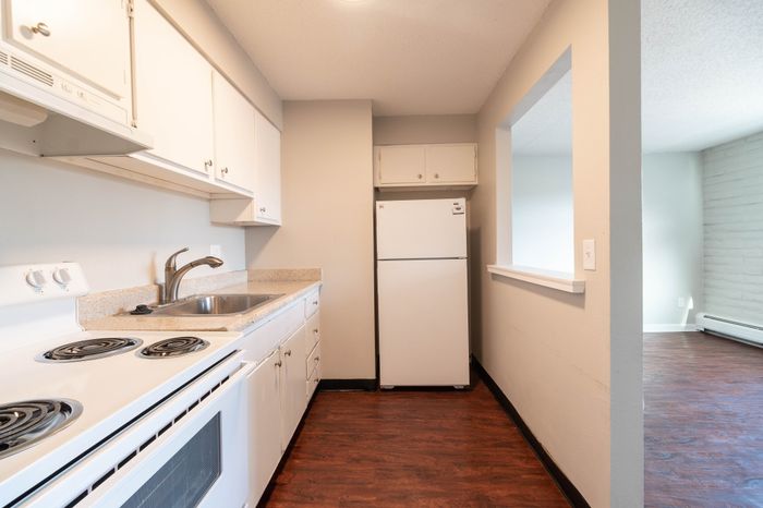 Bright and welcoming kitchen with modern white cabinetry, sleek countertops, and wood-style flooring, perfect for culinary creativity.
