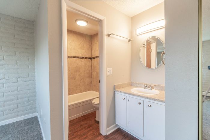 Bright modern bathroom with sleek vanity, elegant lighting, and tiled bathtub for a stylish touch.