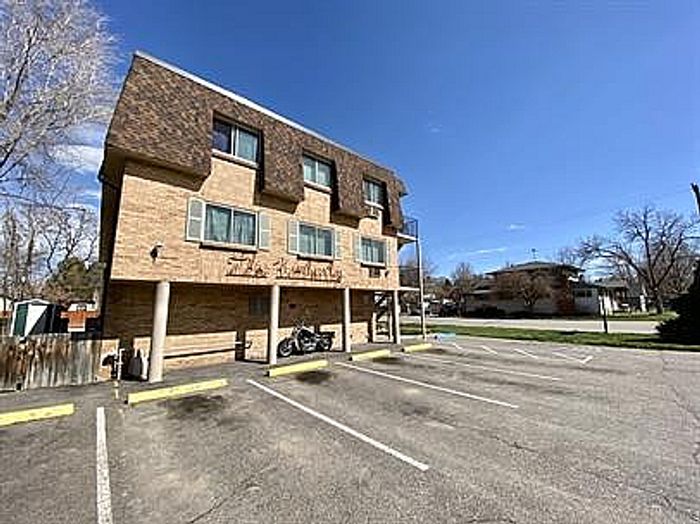 Inviting apartment building with ample parking, nestled in a serene neighborhood with clear blue skies.