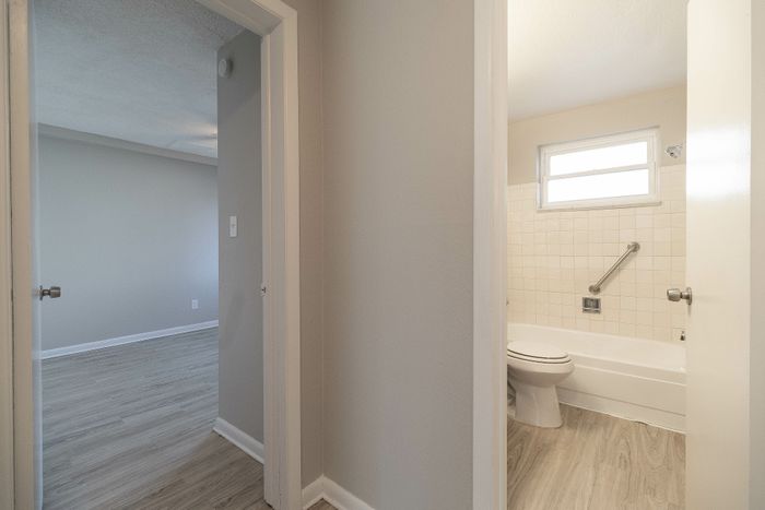 Inviting hallway view featuring a modern bathroom and a spacious bedroom with elegant wood flooring.