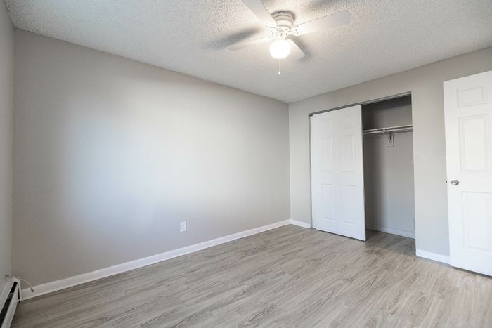 Bright and airy bedroom with sleek wooden floors and a spacious closet, perfect for a modern living setup.