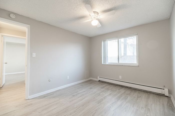 Bright, modern room with elegant wood flooring and a ceiling fan, offering a cozy and inviting space.