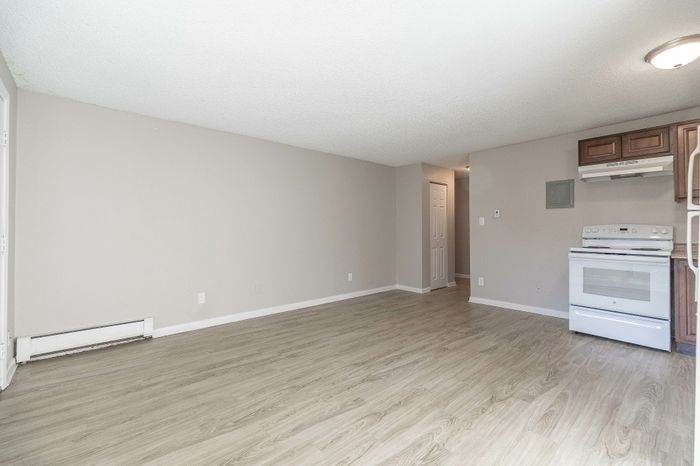 Spacious living area with elegant wood flooring and a sleek kitchen corner featuring modern cabinetry.