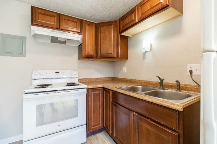 Charming kitchen with rich wooden cabinets, stainless steel sink, and a sleek white oven, perfect for culinary creativity.