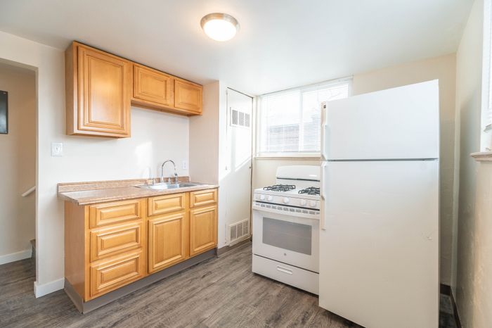 Bright kitchen with modern wood cabinets, sleek countertops, and a spacious layout featuring a large fridge and essential appliances.
