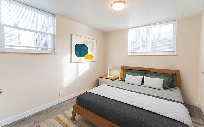 Bright and modern bedroom with stylish decor, featuring a cozy bed, minimalist artwork, and natural light streaming through large windows.