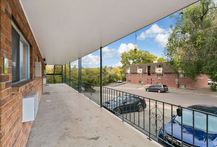 Inviting apartment balcony with scenic views of leafy neighborhood and classic brick buildings, ideal for relaxation.