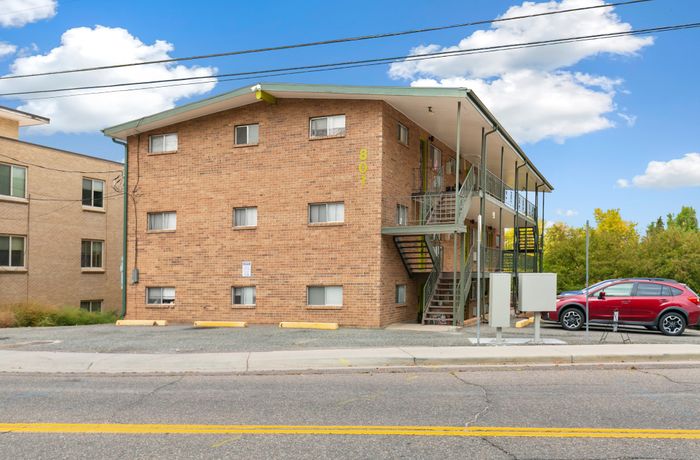 Charming brick apartment building with modern exterior stairs, set against a bright blue sky.
