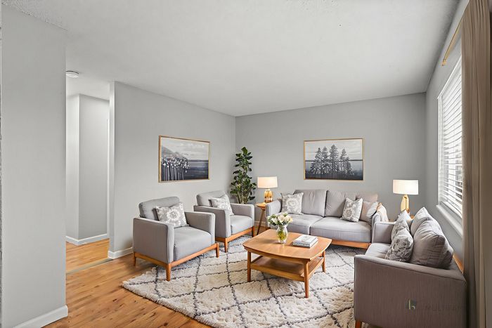Inviting living room with modern decor, featuring plush gray seating, elegant artwork, and abundant natural light.