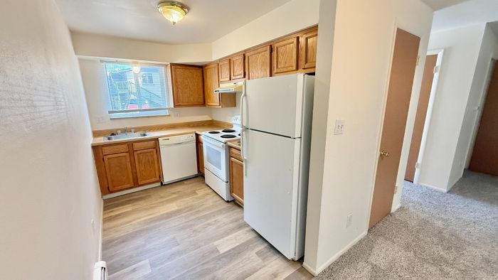 Charming kitchen with warm wooden cabinets, modern appliances, and sleek flooring, perfect for culinary adventures.