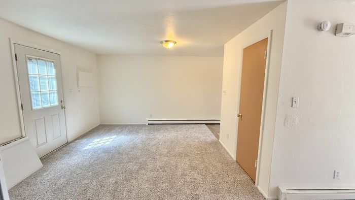Bright and inviting living space with plush carpet and ample natural light, perfect for comfortable living.