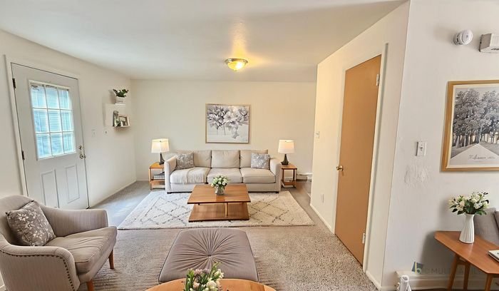 Inviting living room with a modern beige sofa, stylish armchairs, and elegant coffee table, accented by tasteful decor and warm lighting.