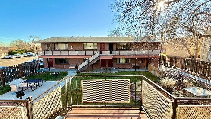 Inviting apartment building with sunlit courtyard, outdoor seating, and a charming landscape view.