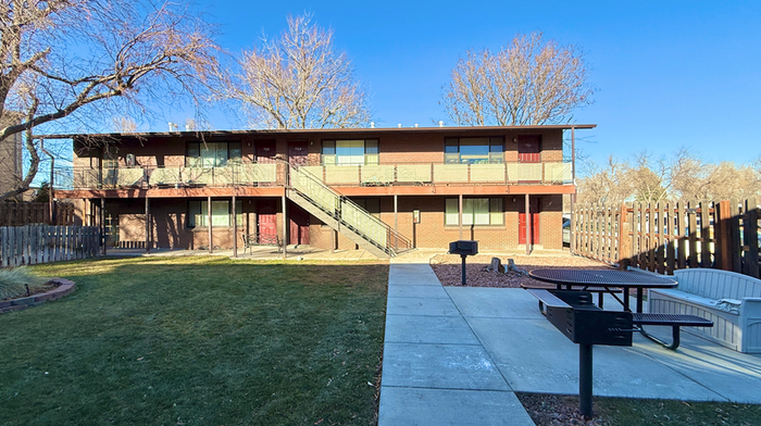 Charming apartment building in a serene neighborhood with inviting outdoor picnic area and manicured lawn.