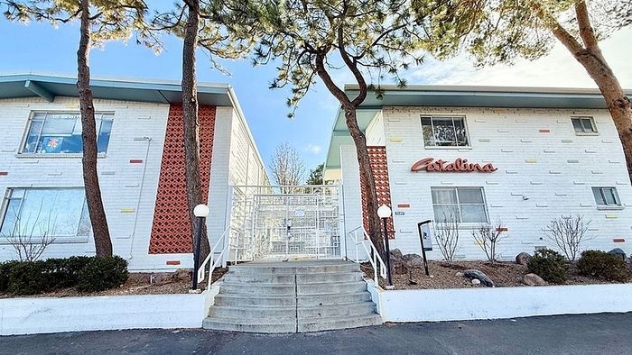 Charming mid-century modern apartment building with unique brick and colorful accents, surrounded by serene landscaping and mature trees.